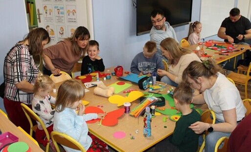 Dzieci i rodzice wykonujący prace plastyczne: ozdabianie motyli